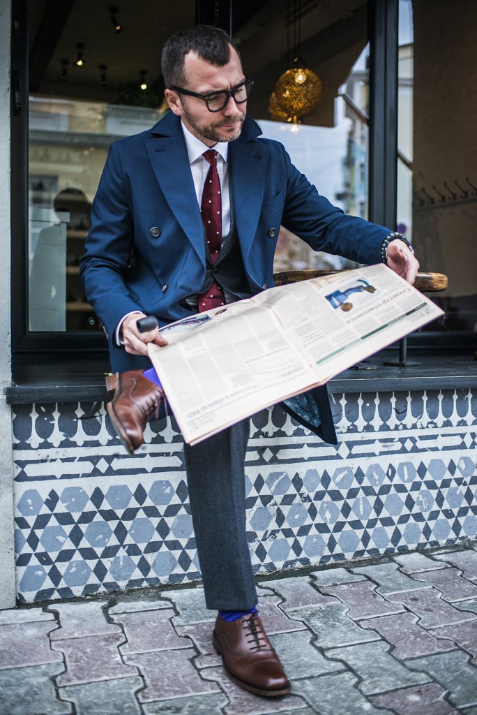 Мужчина в классическом синем костюме читает газету